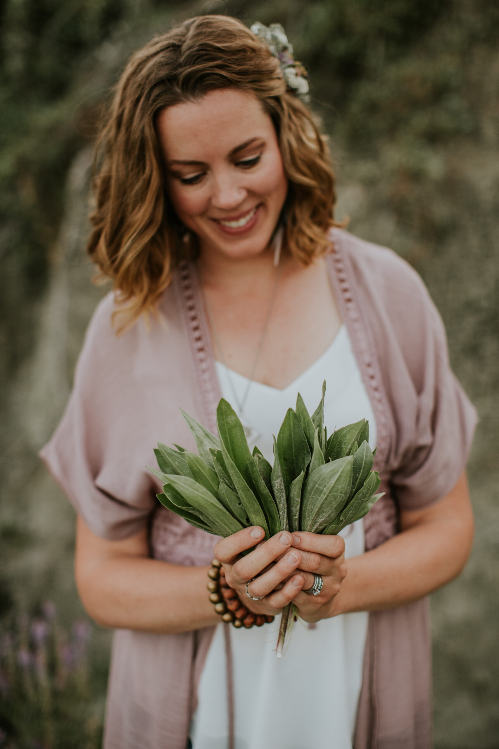 A close-up portrait-oriented image of a person holding green leaves, conveying a natural and organic feel.