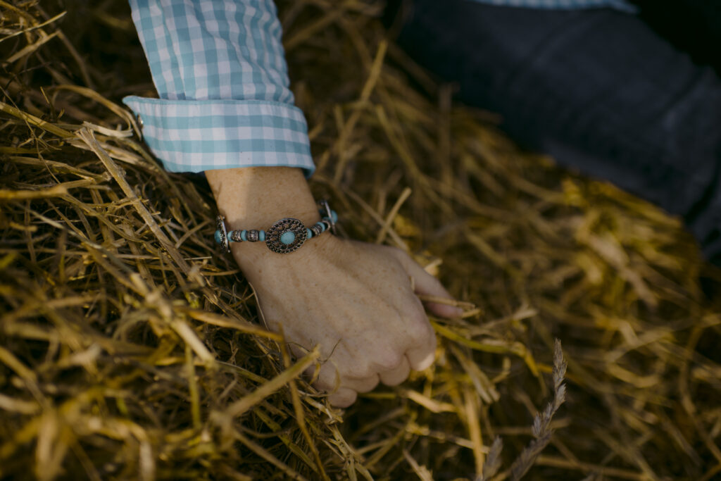 A women's hand in straw wearing a western styled turquoise bracelet. 