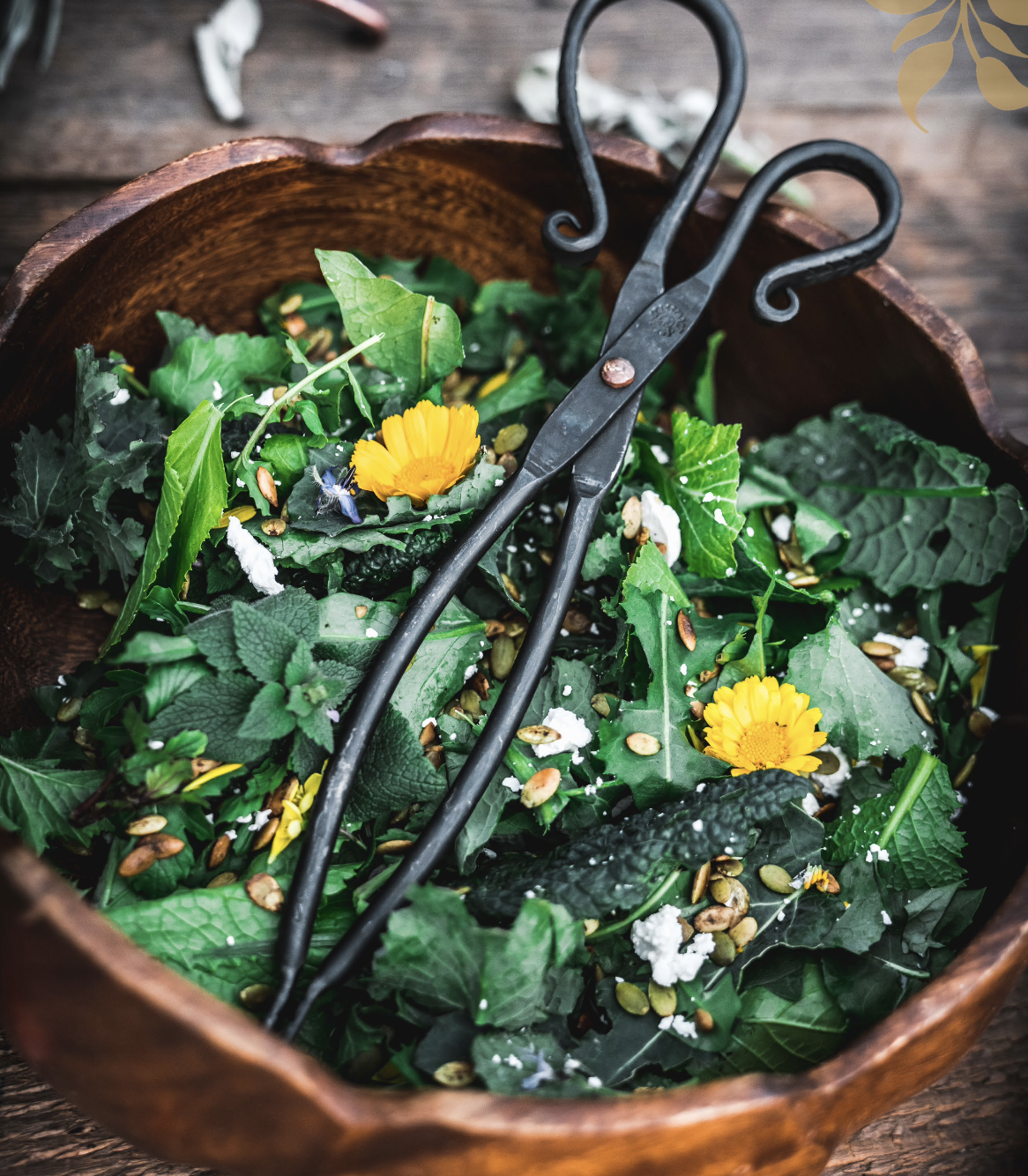 spring salad with greens and spring flowers in a wooden bowl