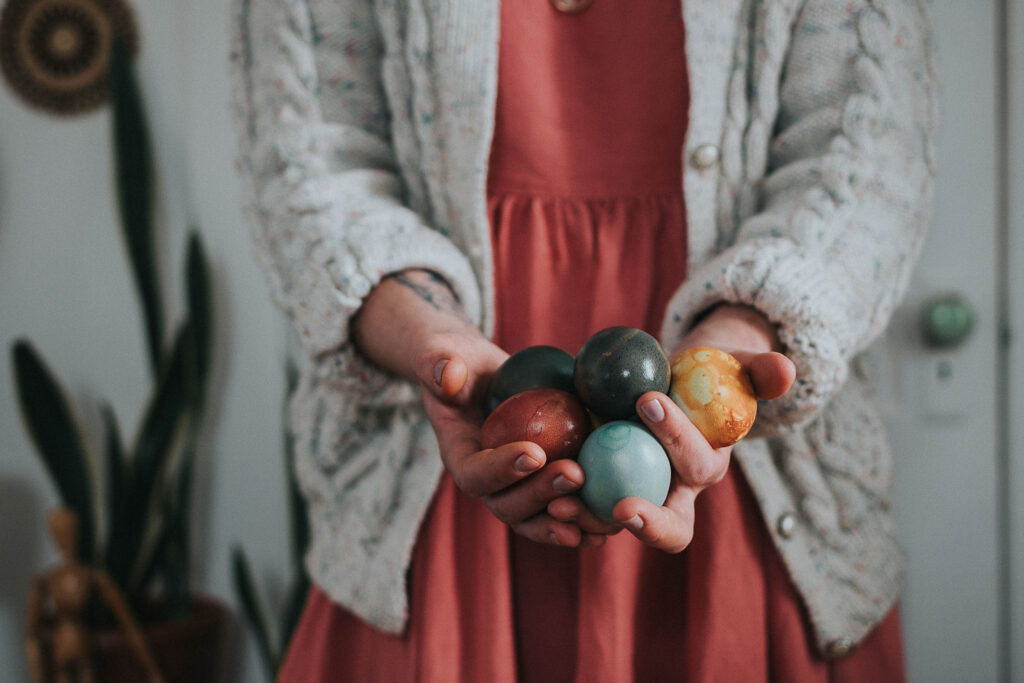 a woman holding naturally dyed eggs