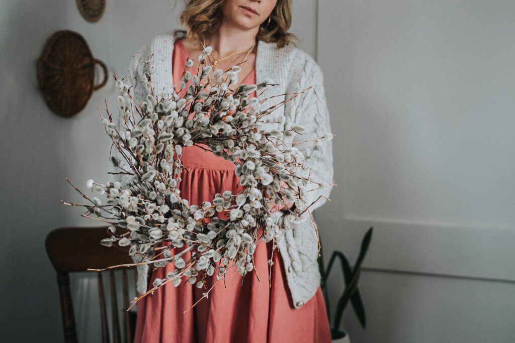 A woman holding up a finished pussy willow wreath/nest