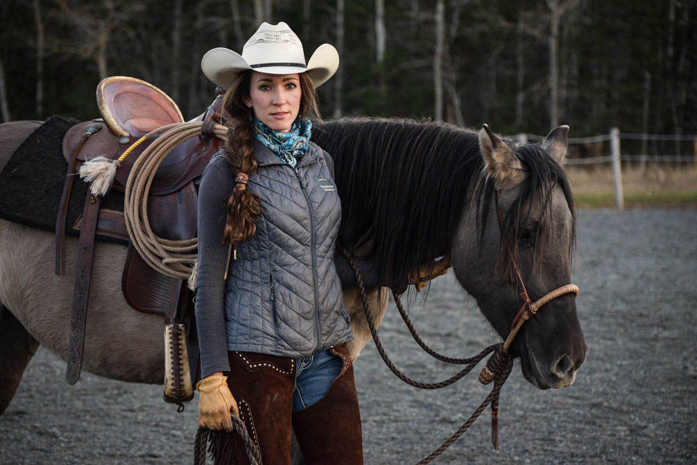 Woman in white hat stands with her horse