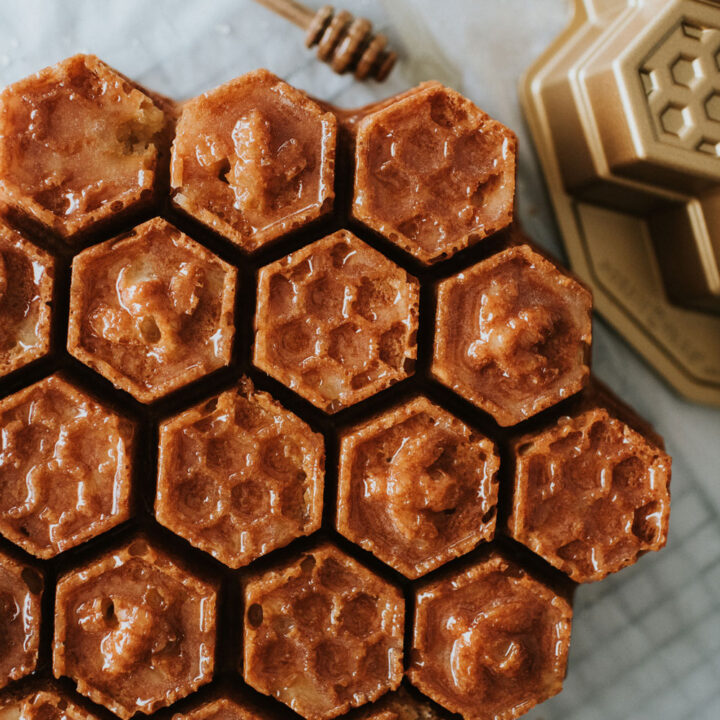 a honeycomb cake sitting on a white tablecloth with a honey stick