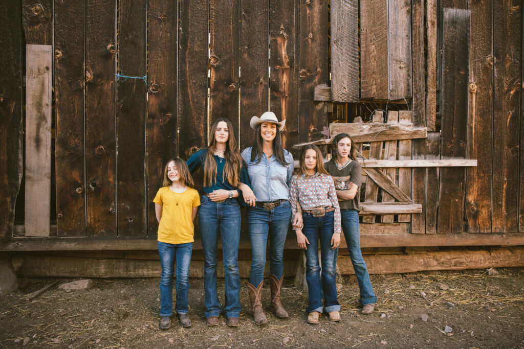 A woman stands with her four daughters in front of a barn