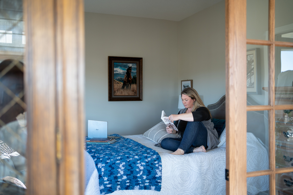 Woman sits on bed reading a book