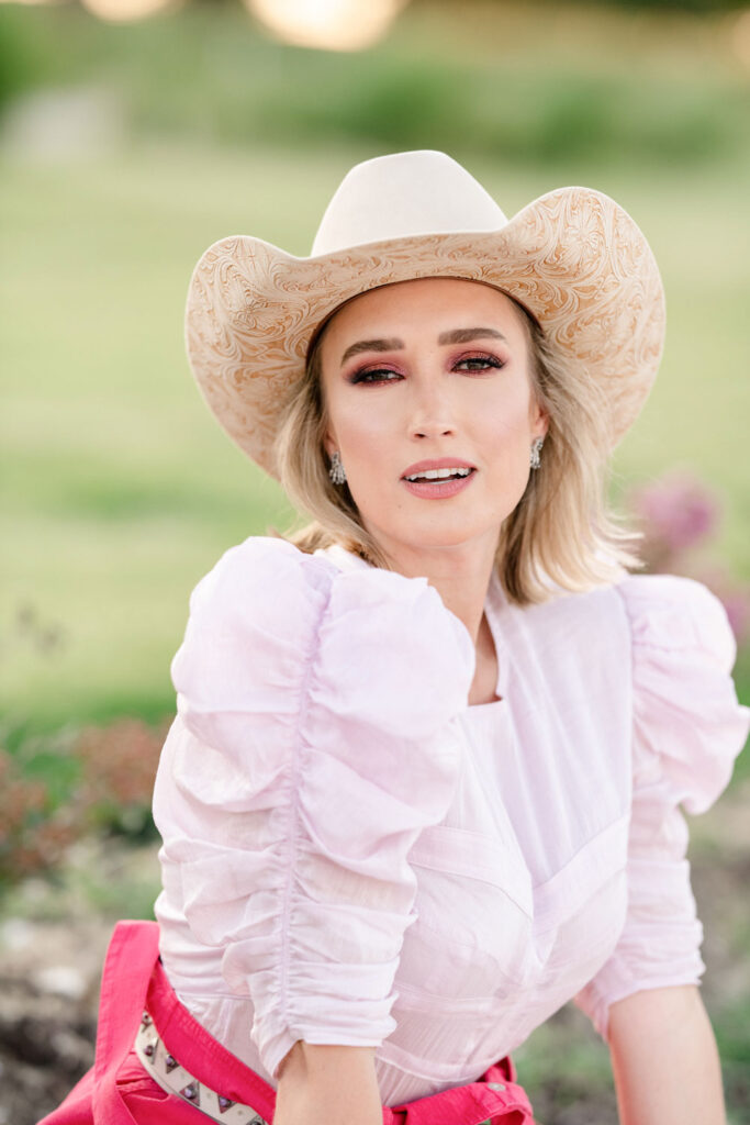 Courtenay DeHoff poses in a pink shirt and a while cowboy hat