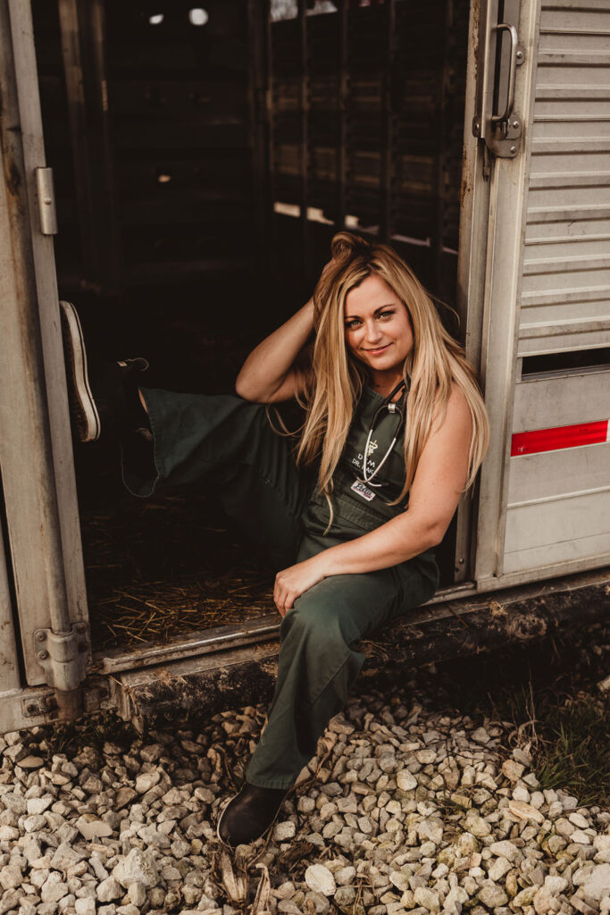 Marissa sits wearing green overalls in the doorway of a trailer