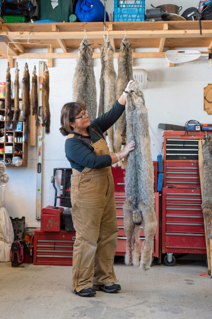 Minnie stands in her workshop looking at fur